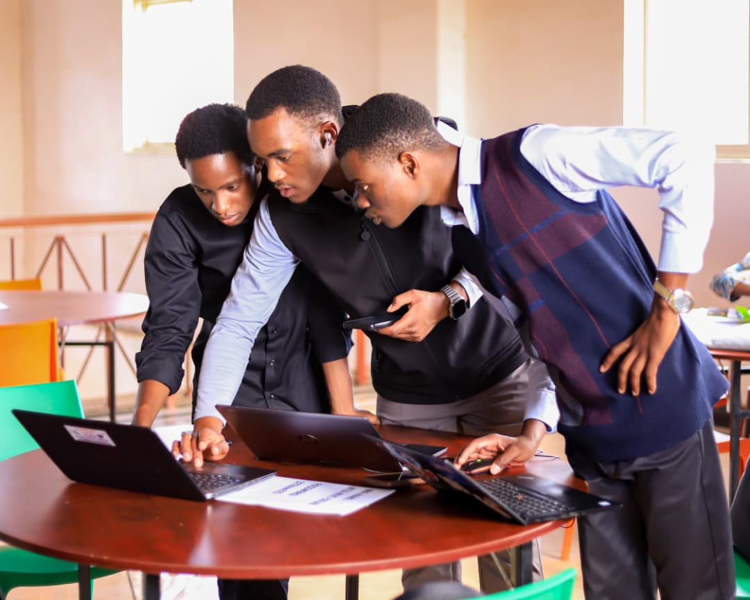 Three participants leaning over one laptop